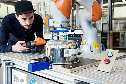 Foto: Studierender des Fachbereichs Industrierobotik justiert Roboter