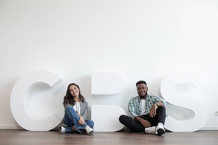 Foto: Studierende sitzen neben großen CBS-Buchstaben