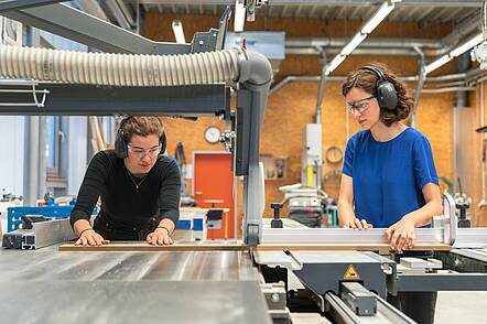 Foto: Studentinnen der Bauhaus-Universität Weimar arbeiten an einer Holzsägemaschine