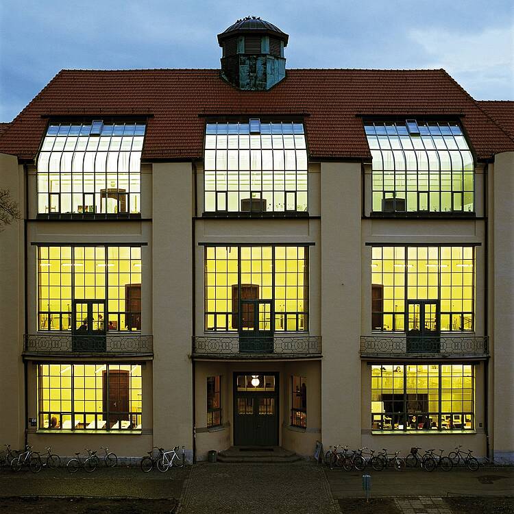 Image: View of the front of the historic main building of the Bauhaus University Weimar at night.