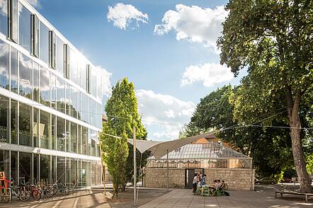 Foto: Studierende sitzen auf dem Campus der Bauhaus-Universität Weimar und unterhalten sich