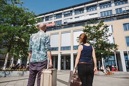 One male and one female student in front of an university building