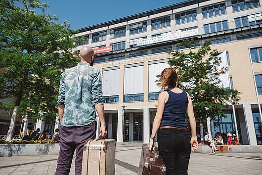 One male and one female student in front of an university building